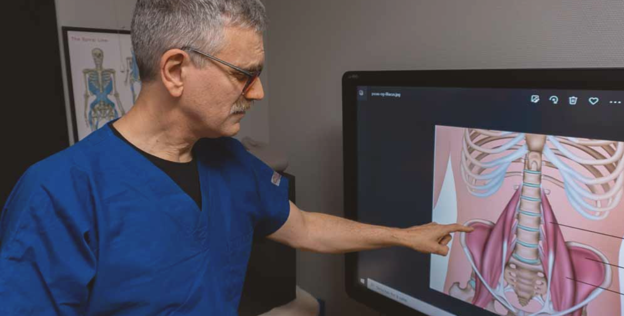 Einar Fagerheim, kledd i en blå t-skjorte, peker på en skjerm som viser et digitalt bilde av anatomien i bekkenet til et menneske. Einar peker på høyre siden av bekkenet.
